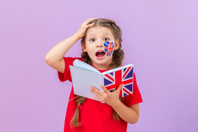 Dziewczynka uczy się angielskiego – trzyma zeszyt z flagą Wielkiej Brytanii, na policzku ma namalowaną brytyjską flagę.